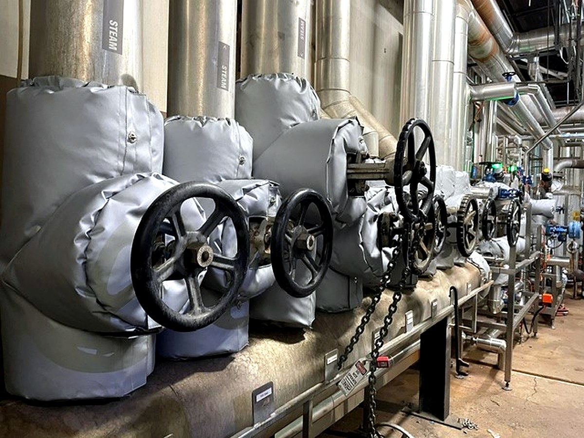Grey thermal jackets fitted to steam system valve assemblies with STEAM labels visible